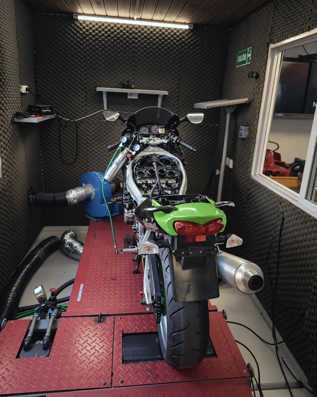 Moto deportiva Kawasaki arriba del banco de pruebas, en la sala insonorizada.