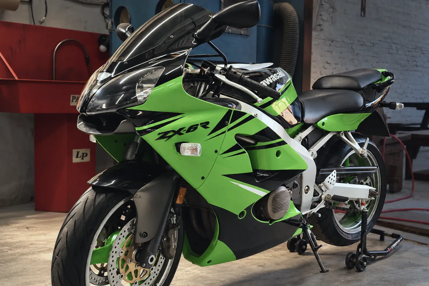 Kawasaki ZX-6R verde sobre caballetes en el taller.