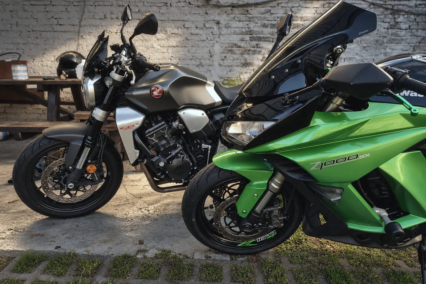 Honda CB1000R gris y Kawasaki Z1000SX verde estacionadas en el patio del taller.