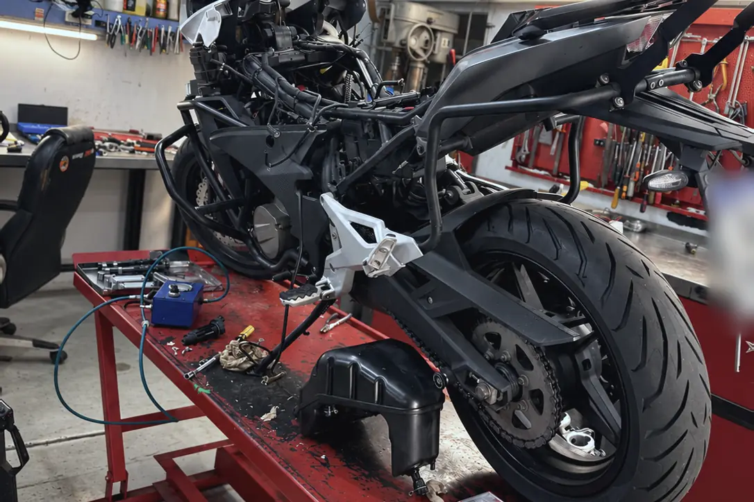 Moto naked desarmada sobre el elevador, con piezas y herramientas a la vista.