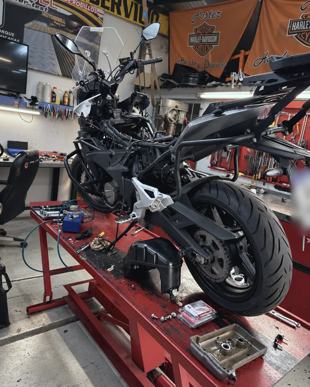 Moto naked desarmada sobre el elevador, con piezas y herramientas a la vista.