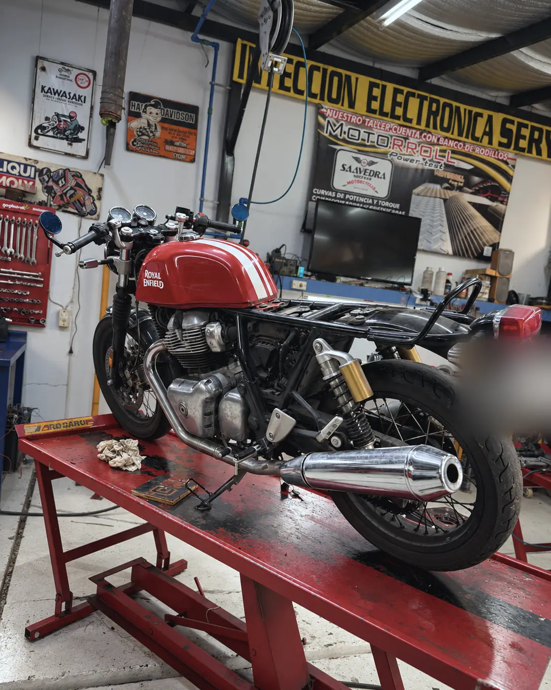 Royal Enfield roja arriba del elevador, con el cartel de inyección electrónica al fondo.
