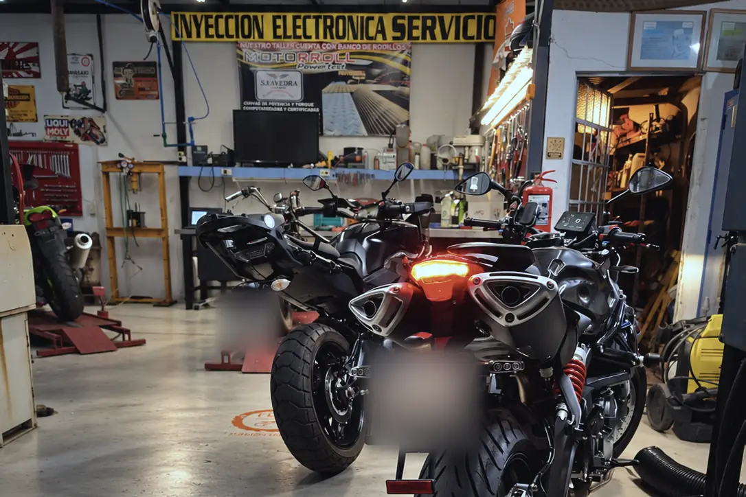 Interior del taller con motos estacionadas y el cartel de inyección electrónica al fondo.