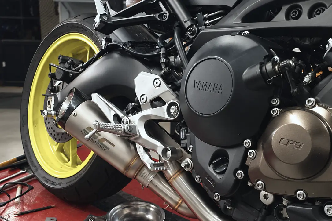 Motor y escape de una Yamaha MT-09 en el elevador, con herramientas sobre la plataforma.