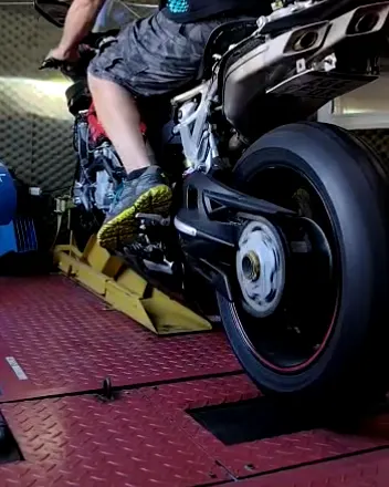 Moto deportiva arriba del banco de pruebas, con la rueda trasera girando sobre el rodillo.
